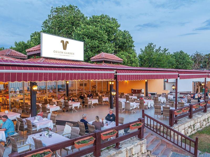 Open outdoor restaurant area with set tables and guests during daylight.