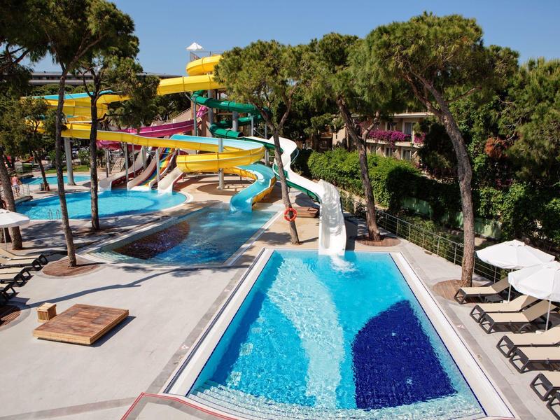 Water park with multiple water slides, pools, and lounge chairs at a hotel resort.