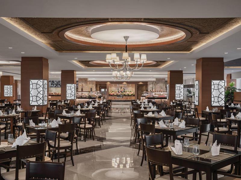 Elegant restaurant with wooden furniture, chandeliers, and dark tiled floor.