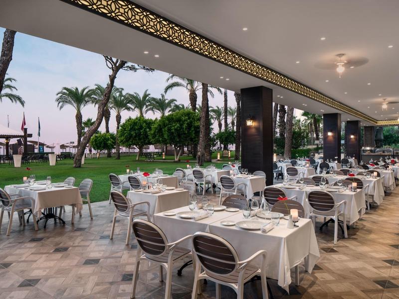 Elegant covered restaurant with white tablecloths and palm trees outside