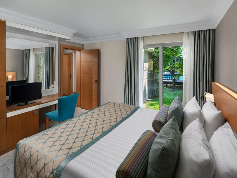 Modern hotel room with comfortable bed, TV, desk, and garden view.