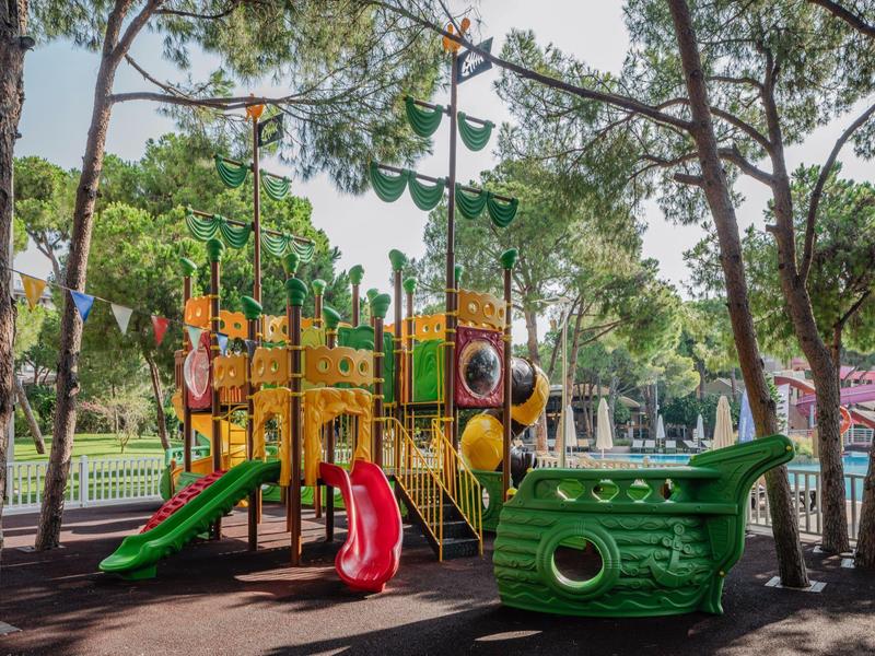 Colorful children's playground with slides and climbing structures among outdoor trees.