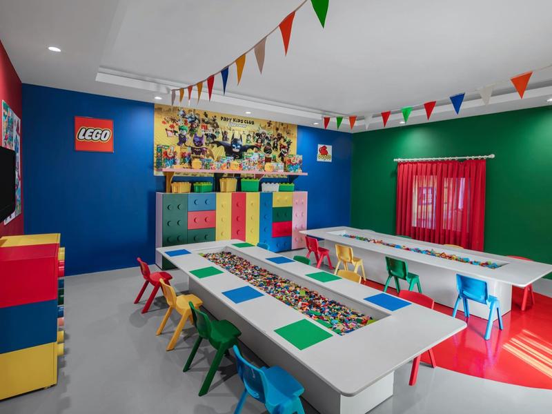 Colorful LEGO-themed kids' playroom with tables and small chairs for creative activities.