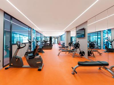 Modern gym with orange flooring and various workout equipment in a hotel.