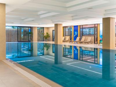 Indoor hotel pool with rectangular basin and lounge chairs by the window