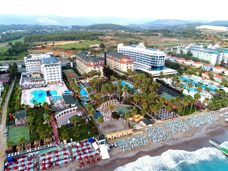 Vista aerea di un grande resort sulla spiaggia con più piscine e accesso diretto al mare.