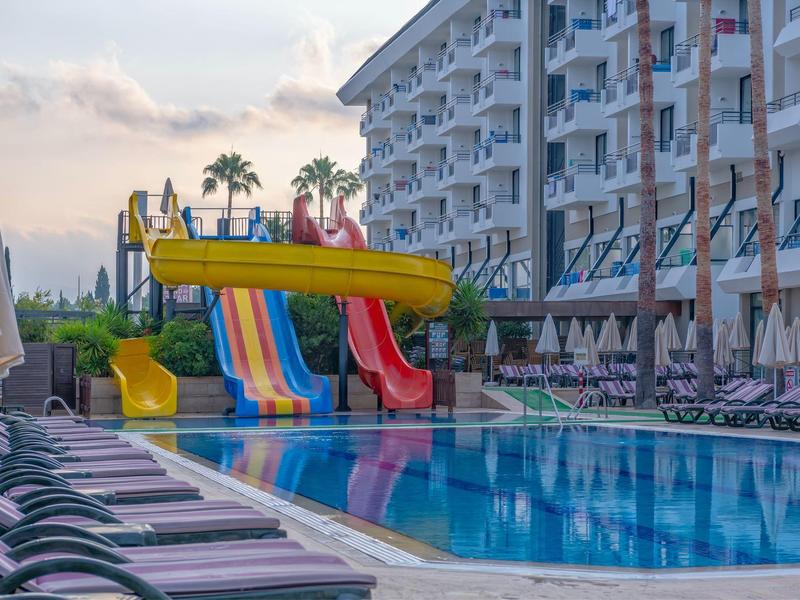 Scivoli d'acqua colorati accanto a lettini e edificio dell'hotel sullo sfondo.