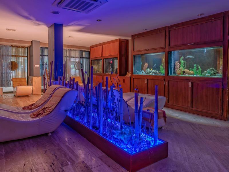 Lounge d'hotel con poltrone moderne e parete di acquario illuminata