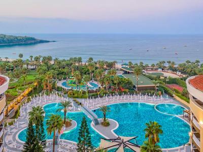 Resort with large pools, palm trees, and sea view at sunset