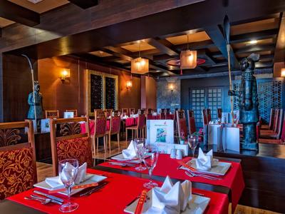 Elegant restaurant interior with red tablecloths and neatly folded napkins on tables.