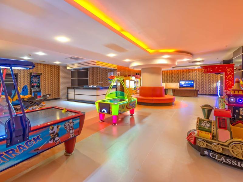 Indoor playroom with arcade games and train ride, bright lighting and colorful decor.