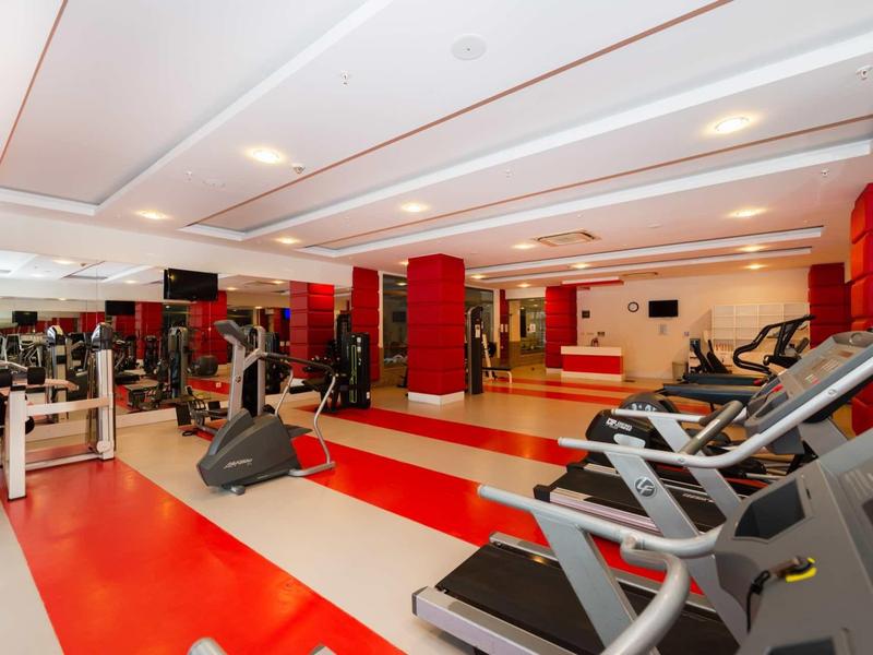 Modern gym with treadmills, exercise bikes, and weight machines in a spacious room.