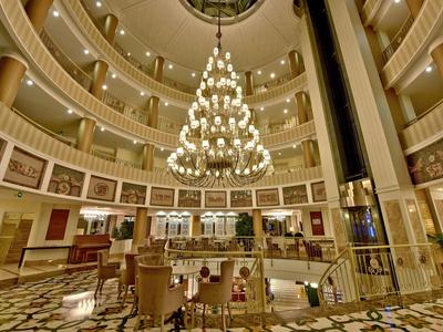 Large circular hotel lobby with multi-level balconies and a grand chandelier in the center.
