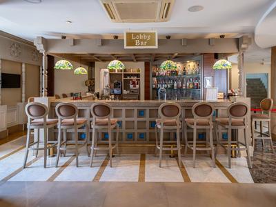 Bright bar area with counter, eight bar stools, and decorative lamps in a modern hotel.