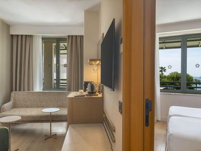 Habitación de hotel cómoda con sala de estar separada y grandes ventanas con vistas.