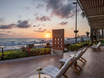 Vista de una terraza en la playa con sillones durante la puesta de sol sobre el mar.