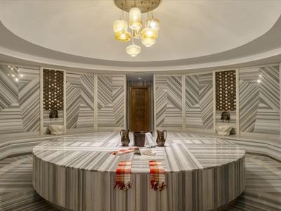 Elegante hammam turco con plataforma central de mármol y paredes decorativas.