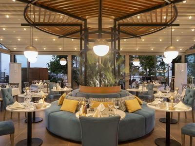 Restaurante moderno y elegante con asientos redondos y techo de madera en un hotel.