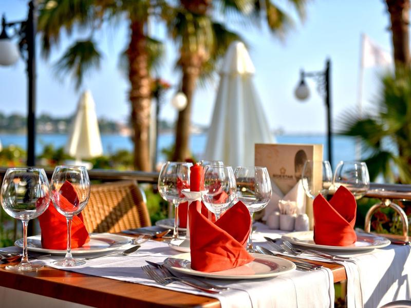 Elegantly set table with red and white napkins and glasses on a seaside terrace.