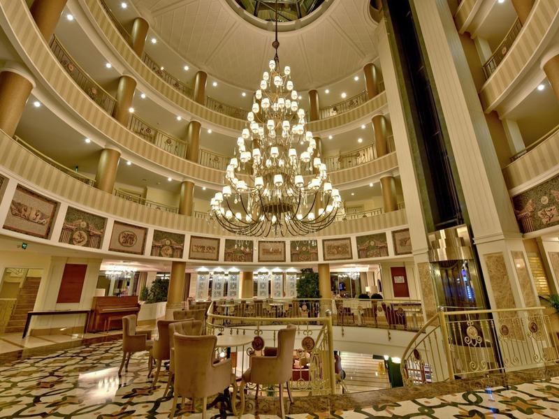 Large circular hotel lobby with multi-level balconies and a grand chandelier in the center.