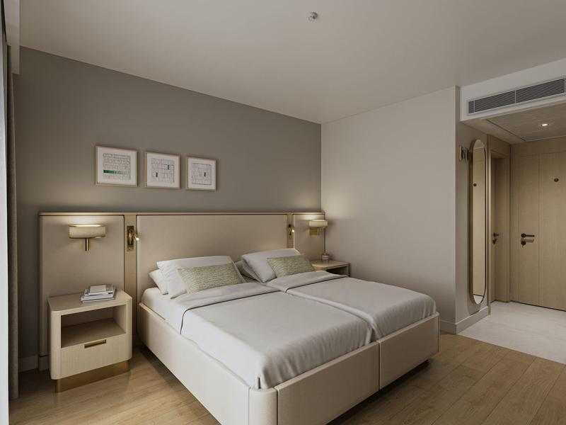 Modern hotel room with two single beds, bedside table, and minimalist decor.