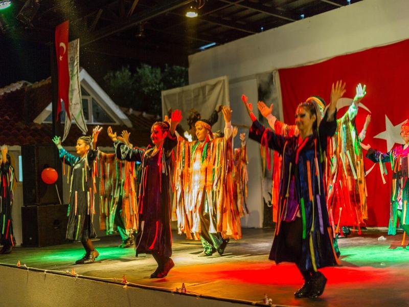 Several people in colorful costumes perform a show on a lit stage.