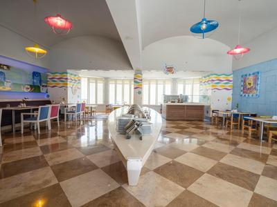 Sala colazione luminosa e colorata con tavoli, sedie e luci decorative in un hotel.