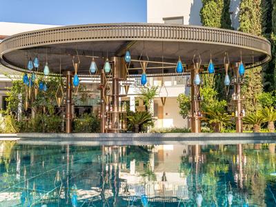 Padiglione moderno accanto a una piscina con luci blu e piante verdi sullo sfondo