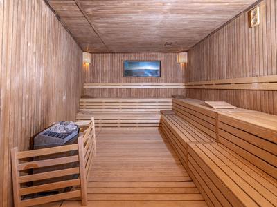 Vista interna di una sauna con pannelli di legno e panche su entrambi i lati.