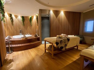 Accogliente spa con pavimento in legno, lettino da massaggio, vasca da bagno e illuminazione soffusa.