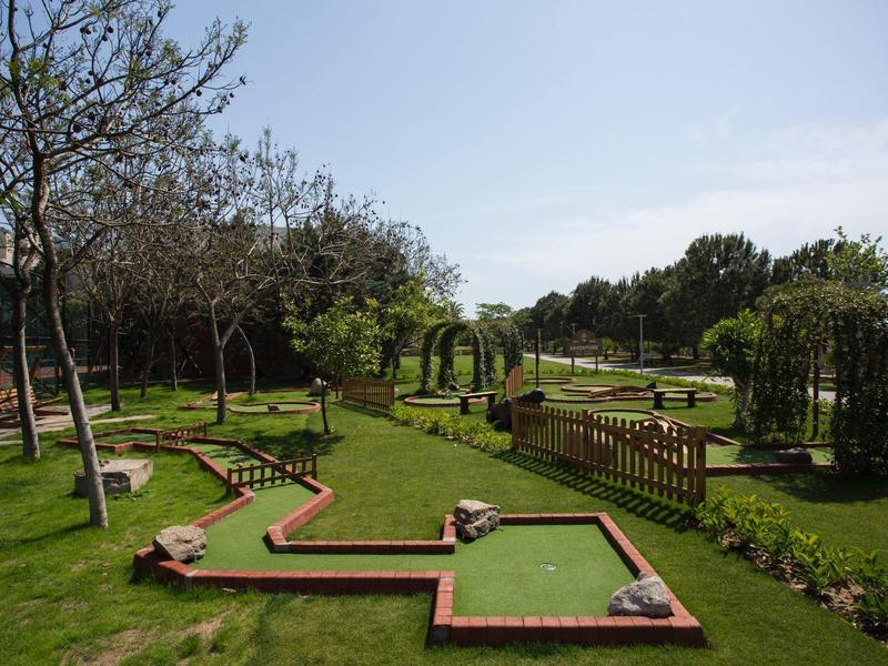 Percorso da mini golf verde con varie piste e alberi nel giardino dell'hotel.