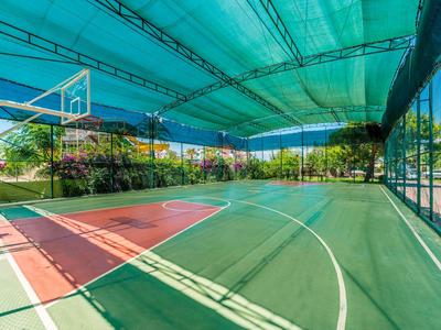 Cancha de baloncesto cubierta con suelo verde y líneas blancas en un complejo turístico.