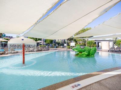 Piscina per bambini con gioco d'acqua e ombrelloni in una struttura alberghiera.