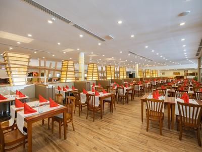 Ampia sala da pranzo luminosa con sedie in legno e decorazioni da tavolo rosso-bianco