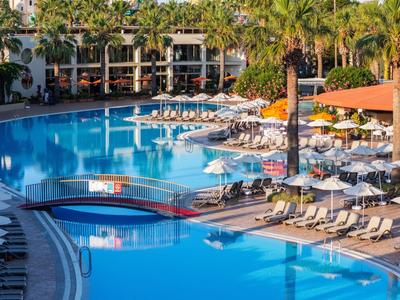 Groot buitenzwembad met ligstoelen en parasols bij een hotelresort.