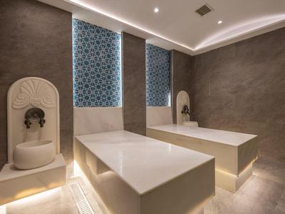 Moderne wellnessruimte met twee witte marmeren ligbedden en decoratieve wandelementen.