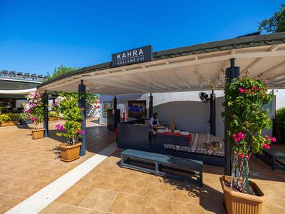 Moderne buitenzitplek van hotel met paviljoen, planten en heldere blauwe lucht.