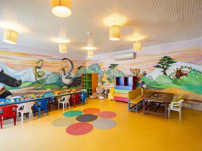 Kleurrijke speelkamer voor kinderen met beschilderde muren, kleurrijke tafels en stoelen in een hotel.