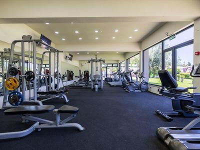 Moderne fitnessapparatuur in een lichte, ruime fitnessruimte met grote ramen.