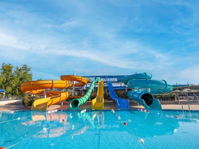 Waterpark met meerdere kleurrijke glijbanen en een groot zwembad onder een heldere lucht.