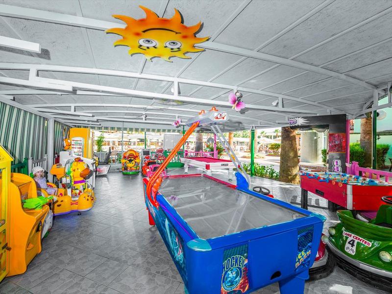 Spazio interno con attrezzature da gioco colorate e piccole auto in una struttura ricreativa.