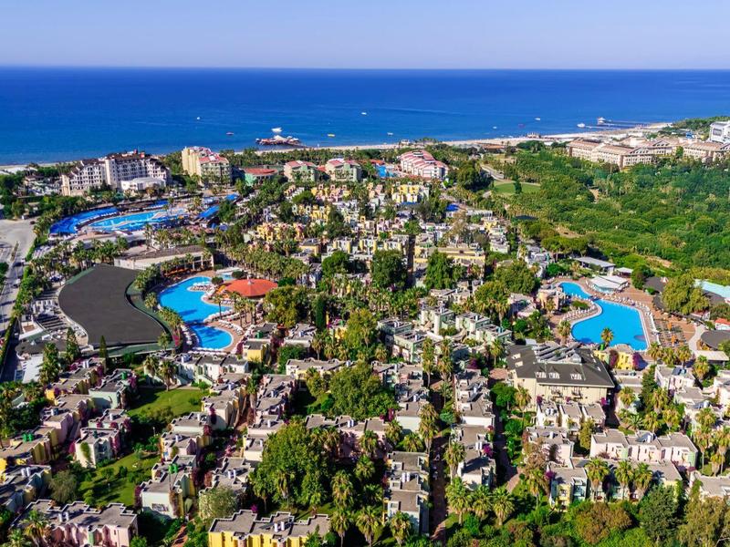 Veduta aerea di una città costiera con hotel, piscine e mare vicino.