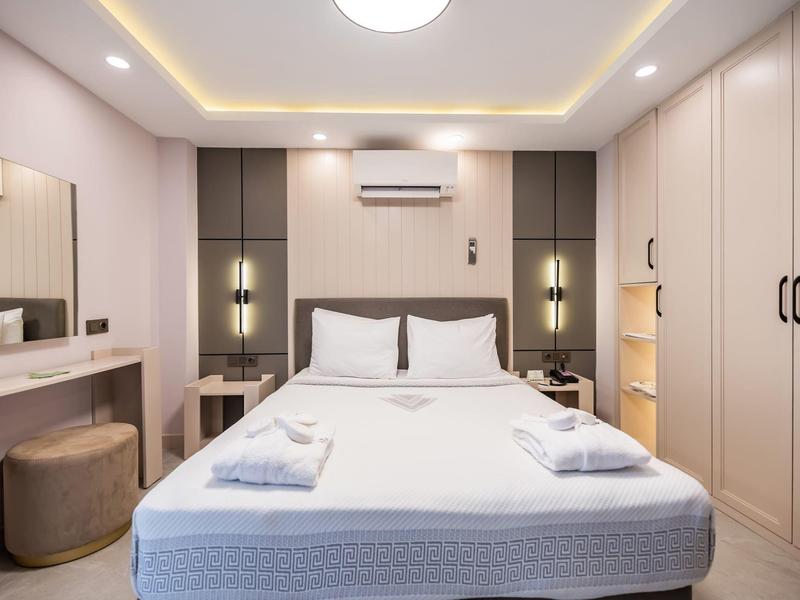 Camera d'hotel moderna con letto matrimoniale, scrivania, sgabello e aria condizionata.