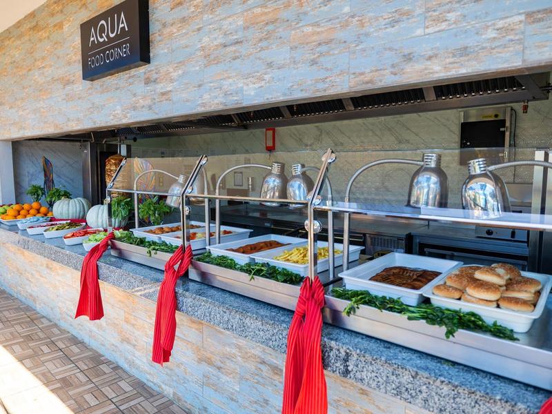 Buffet con coperchi sui vassoi del cibo e verdure fresche in un'area esterna di un hotel.