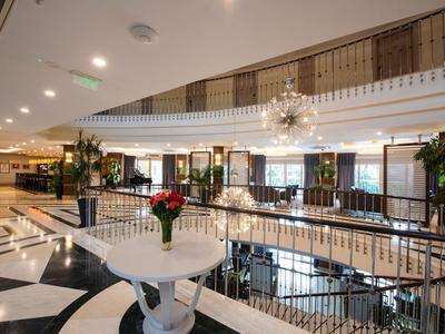 Eleganter Innenraum mit weißem Rundtisch, roten Rosen, schwarzen und weißen Fliesen und Kronleuchtern.