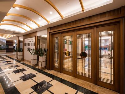 Eleganter Hotelflur mit dunkelbraunen Holztüren und cremefarbenem Marmorboden mit schwarzen Akzenten.