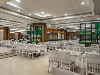 Großer, heller Speisesaal mit weißen Stühlen und Tischen, modernem Design und vielen Sitzplätzen.