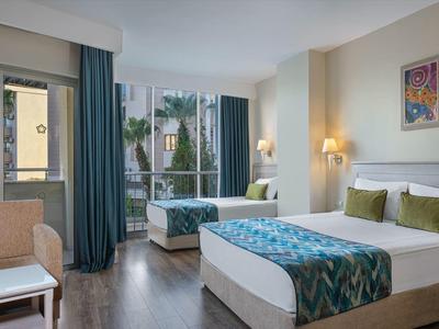 Modernes Hotelzimmer mit Doppelbett, Sitzbereich und großem Fenster mit Blick auf Nachbargebäude.