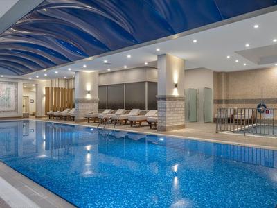 Moderner Innenpool mit blauen Wänden und bequemen Liegestühlen in einem Hotel.