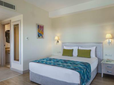 Helles Hotelzimmer mit Doppelbett, weißen Wänden und zwei Nachttischen mit Lampen.